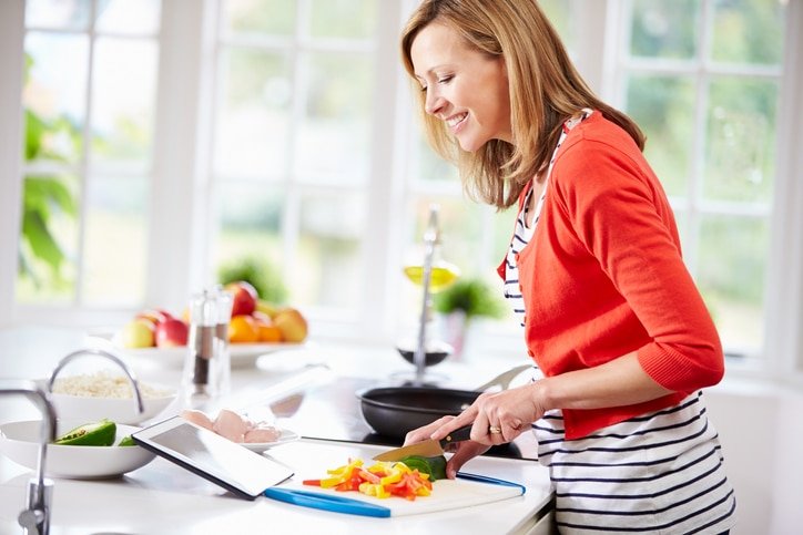 Woman in Kitchen Cooking Healthy to Avoid Metabolic Damage