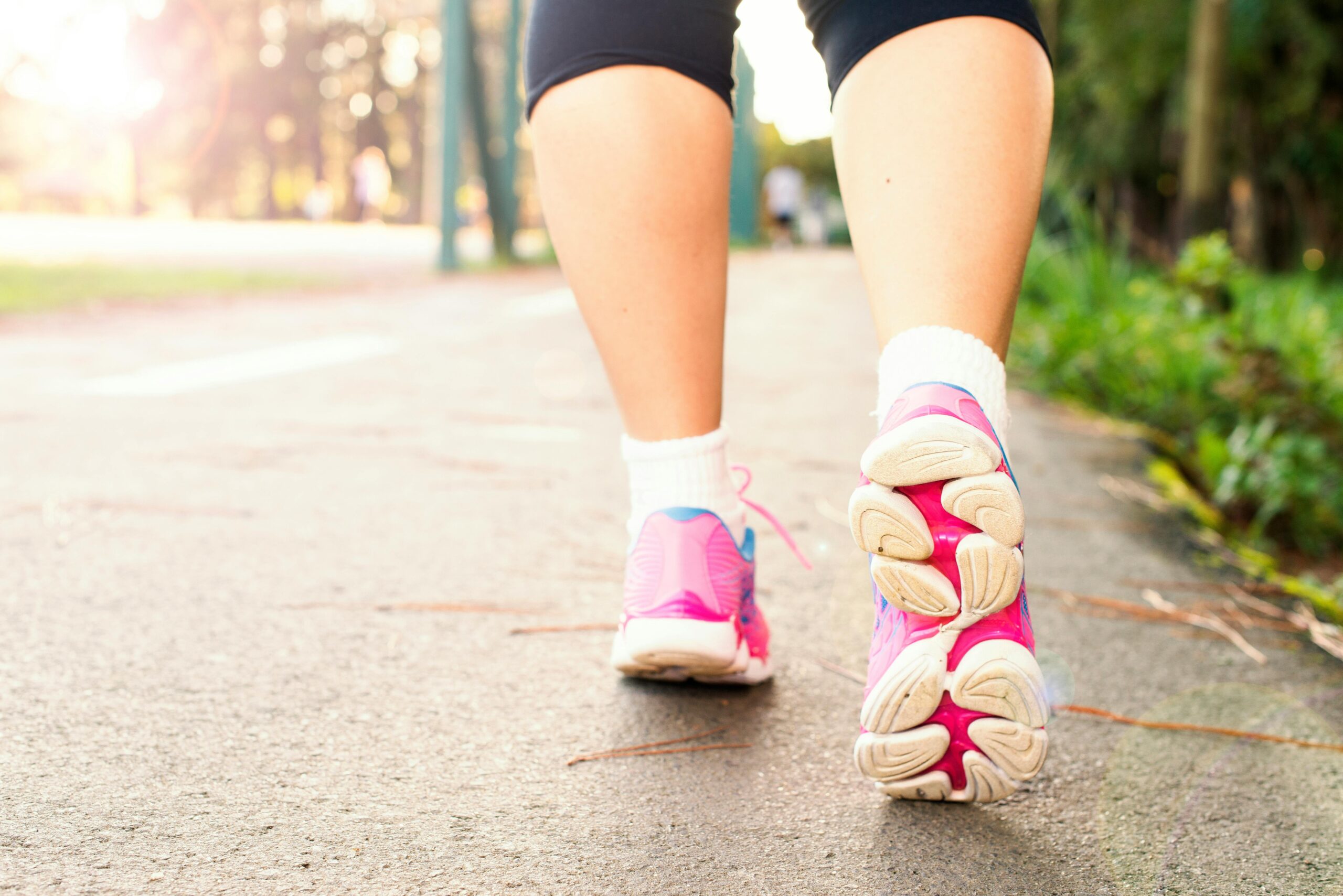 Close-up of a woman walking on a path in pink sneakers, embracing fitness and an active lifestyle.