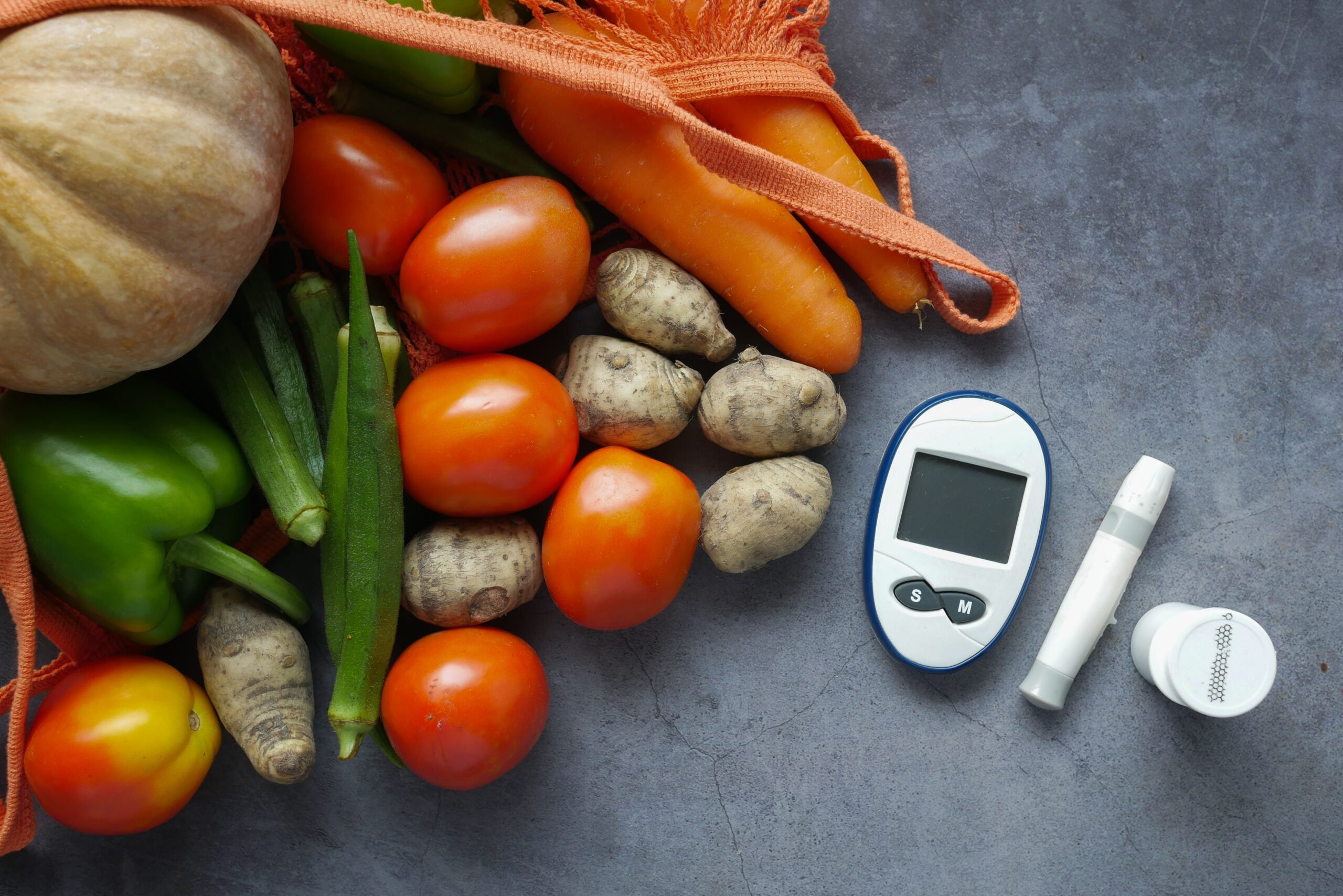 Mesh bag of fresh vegetables next to a glucose meter and lancet, showing blood sugar monitoring during treatment with weight loss injections.